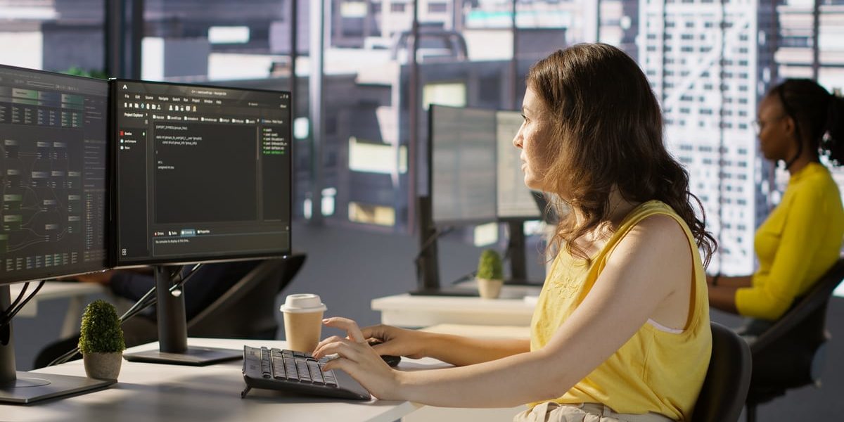 Woman at computer in a large office.