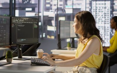 Woman at computer in a large office.